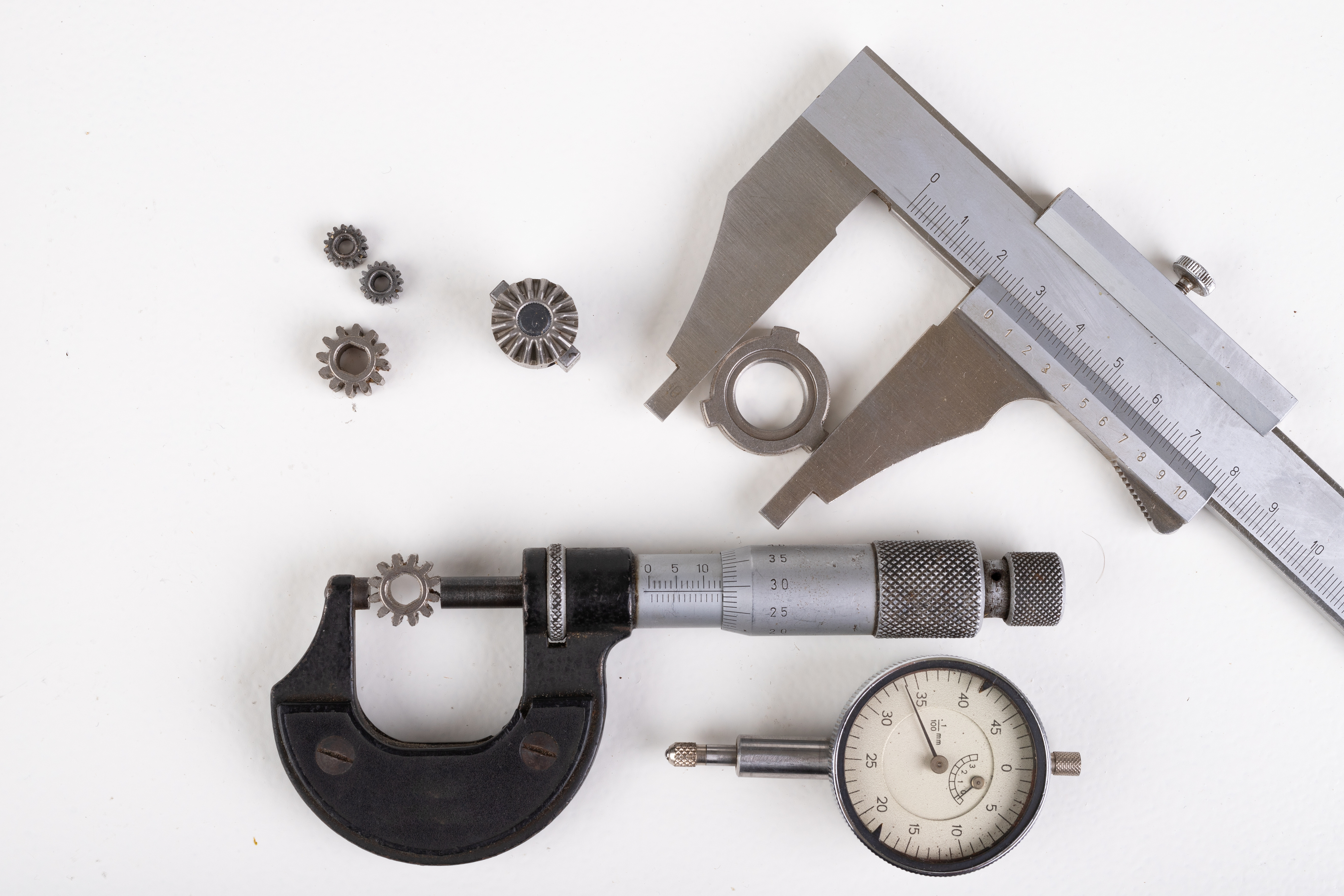 Micrometer, caliper and gear wheels for measurements. Workshop accessories. Light background.