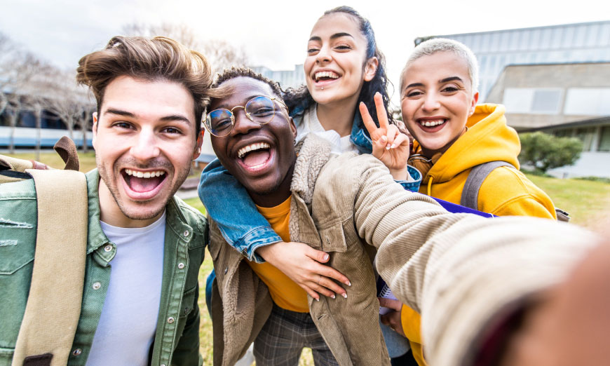 Grupo de jovenes se toma una selfi sonriendo hacia la camara