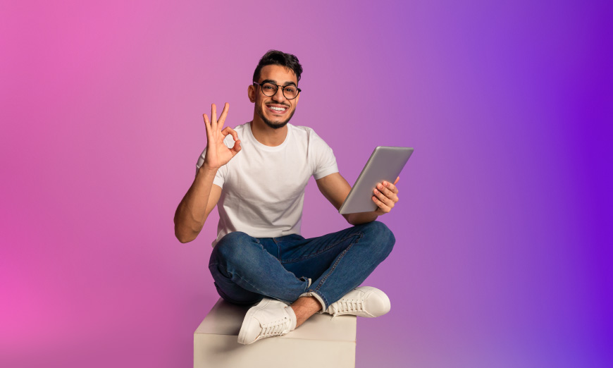 Hombre sentado en un cubo sujetando una tablet