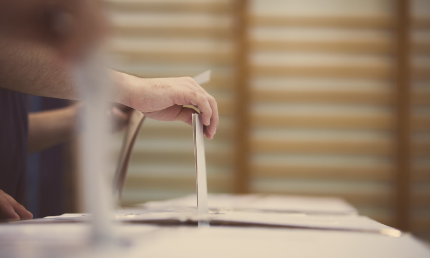 Manos depositando votos en urna