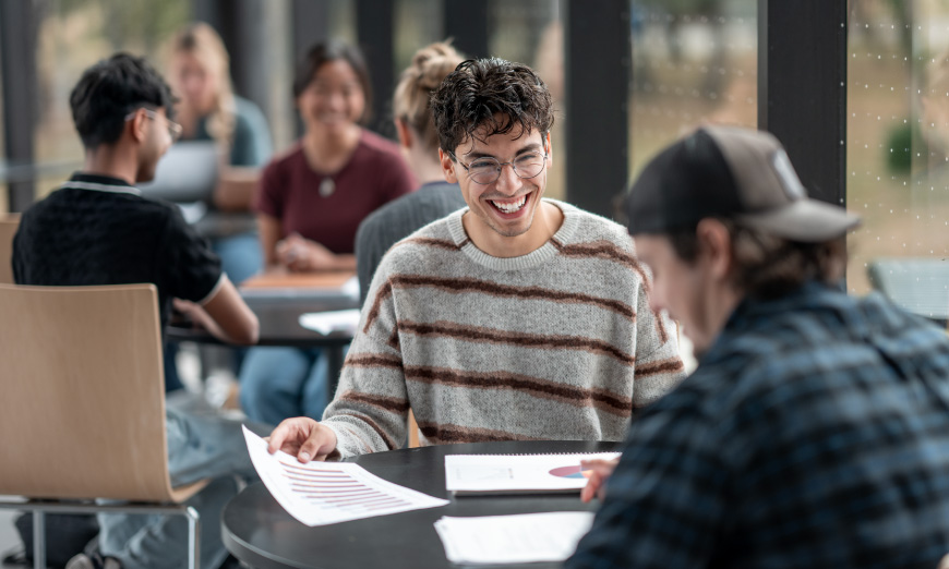 Estudiantes sonriendo con papeles en la mano